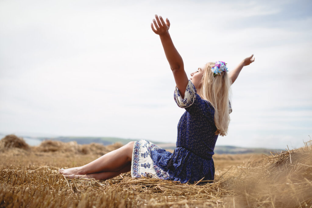 Frau in der Natur, die innehält, um auf ihre innere Stimme zu hören und neue Kraft zu finden.