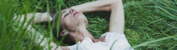 Frau in der Natur, die innehält, um auf ihre innere Stimme zu hören und neue Kraft zu finden.