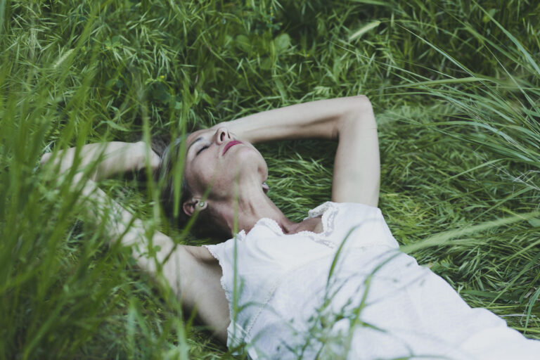 Frau in der Natur, die innehält, um auf ihre innere Stimme zu hören und neue Kraft zu finden.